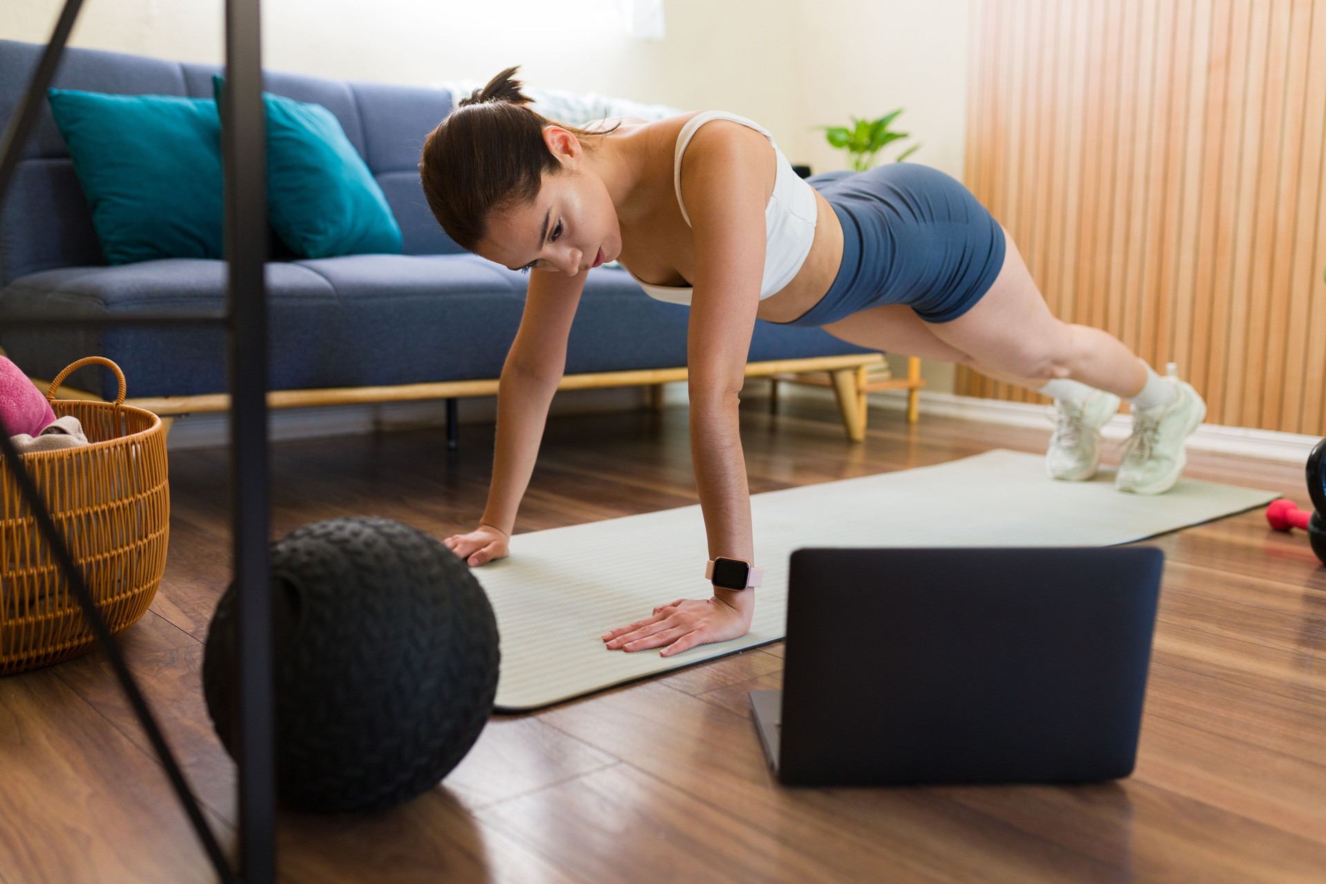 Fit woman doing push-ups while following online workout at home